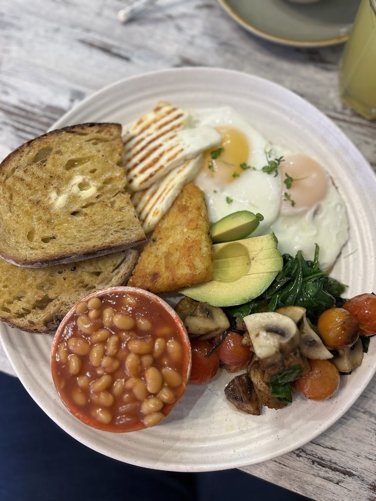 Loaded brunch plate with toast, poached eggs, avocado, spinach, mushrooms and beans